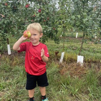 Boy holding an apple up to his eye.